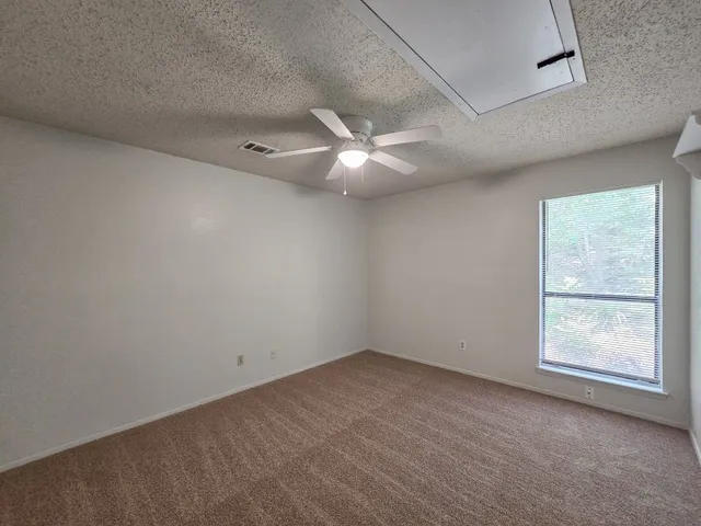 an empty room with a ceiling fan and a window
