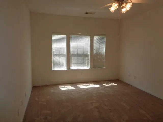 a view of a big room with windows and chandelier fan
