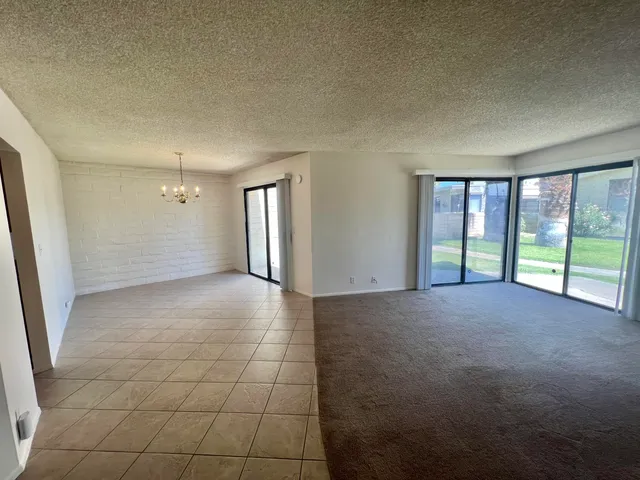 a view of a big room with windows and chandelier fan