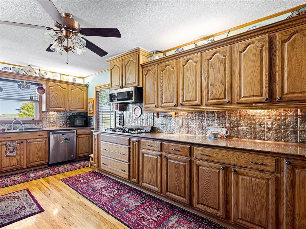 117 County Road 2646 Decatur, TX 76234 - Photo 12 of 39 a kitchen with stainless steel appliances granite countertop a refrigerator a sink dishwasher a stove with wooden cabinets and floor