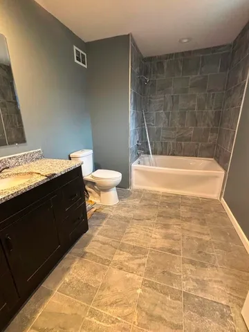a bathroom with a granite countertop bathtub sink and toilet