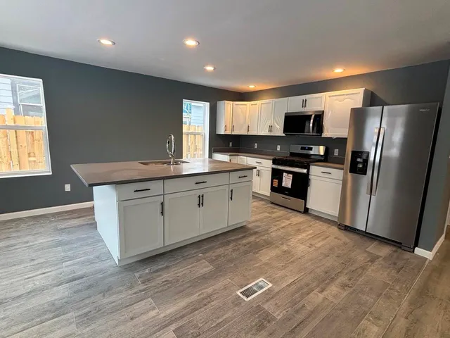 a kitchen with stainless steel appliances granite countertop a stove a sink dishwasher a refrigerator and a microwave