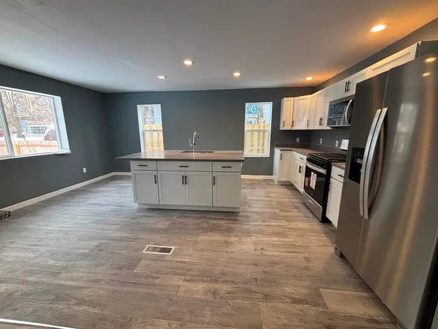 a view of kitchen with stainless steel appliances granite countertop a refrigerator and a sink