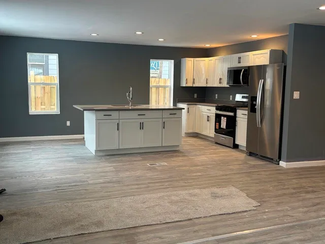 a large kitchen with granite countertop a stove a sink and a refrigerator