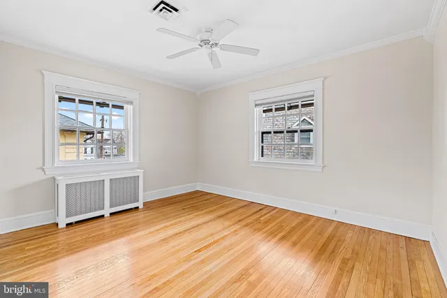 a view of an empty room with window and wooden floor