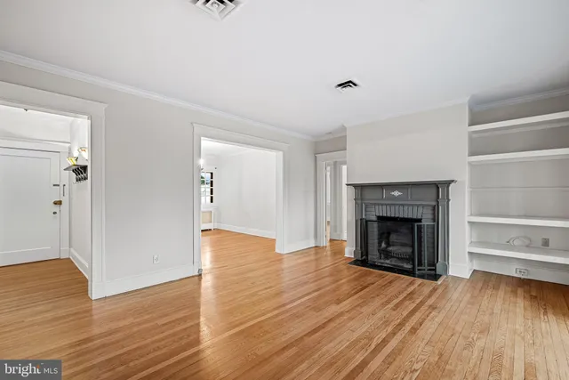 a view of an empty room with wooden floor fireplace and a window