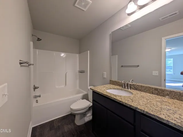 a bathroom with a granite countertop sink a toilet and shower