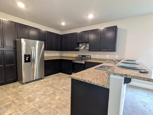 a kitchen with stainless steel appliances granite countertop a sink stove and refrigerator