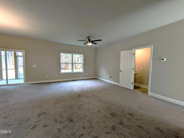 an empty room with windows and ceiling fan