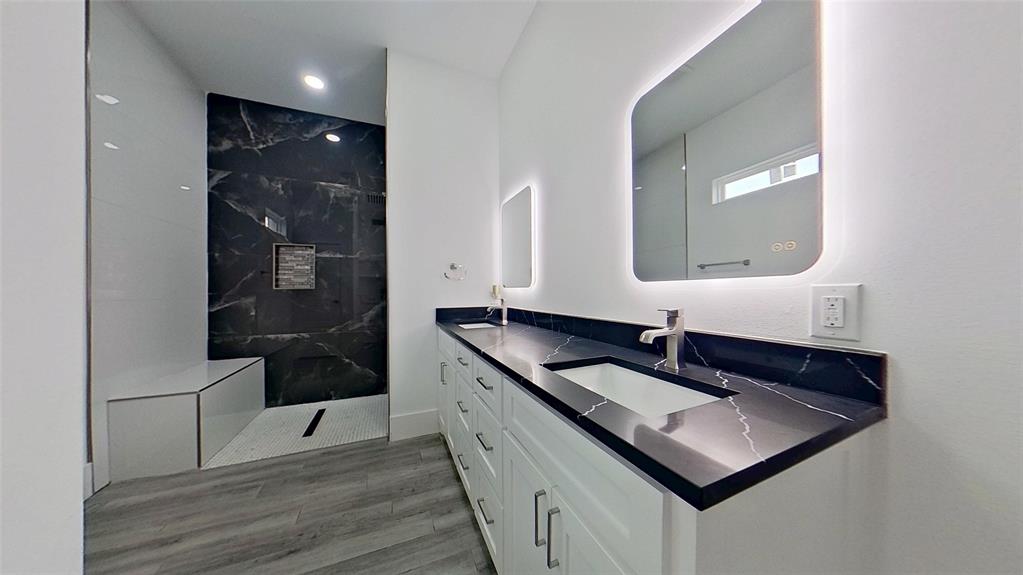 3248 North Cardinal Road Azle, TX 76020 - Photo 23 of 29 Contemporary bathroom featuring a dual vanity with dark stone countertops, undermount sinks, and illuminated mirrors
