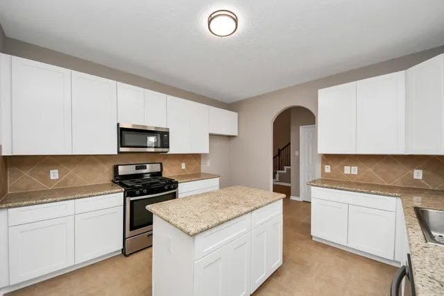 a kitchen with granite countertop a sink stove and white cabinets