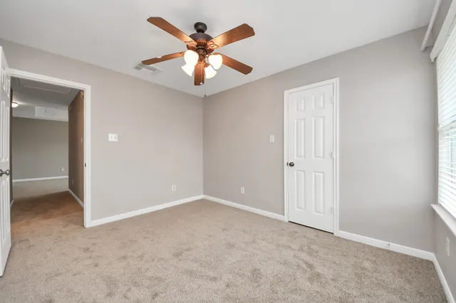 an empty room with windows and fan