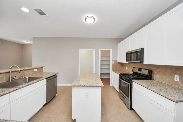 a kitchen with granite countertop a sink and stainless steel appliances