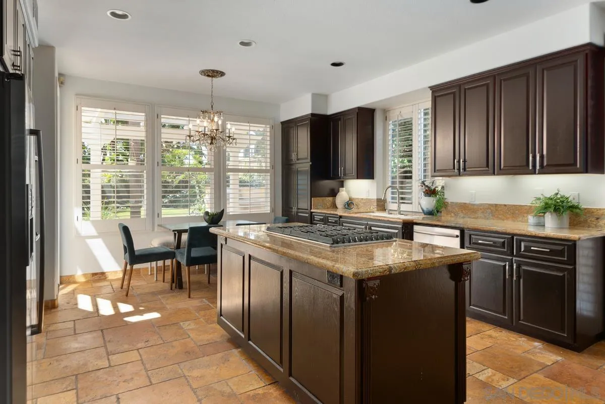 4889 Riding Ridge Road San Diego, CA 92130 - Photo 15 of 34 a kitchen with granite countertop sink stove and white cabinets