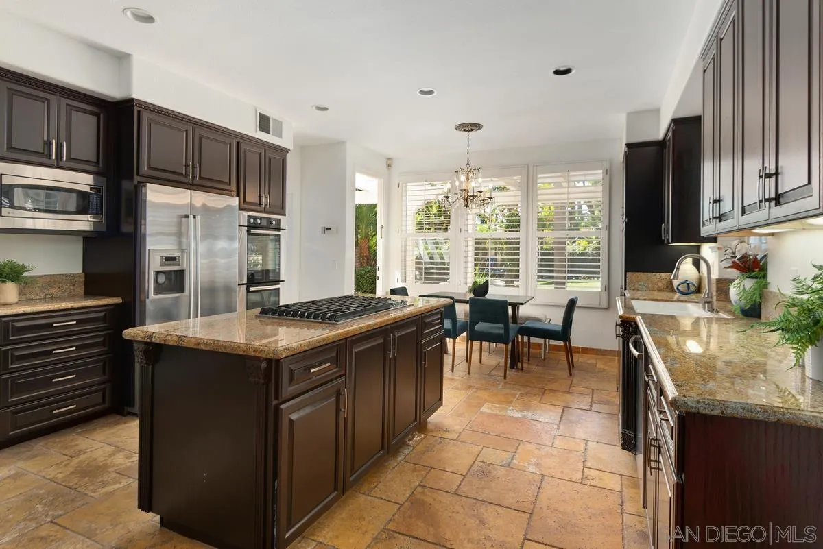 4889 Riding Ridge Road San Diego, CA 92130 - Photo 16 of 34 a kitchen with kitchen island granite countertop a stove a sink and a refrigerator