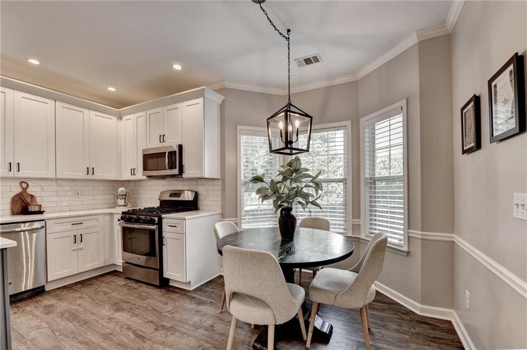1130 Rome Drive Roswell, GA 30075 - Photo 43 of 96 a kitchen with stainless steel appliances a dining table chairs and white cabinets