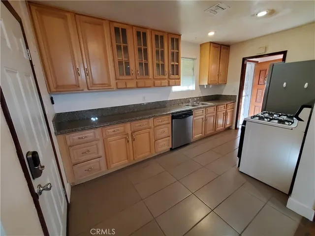 a kitchen with granite countertop a refrigerator a sink and wooden cabinets