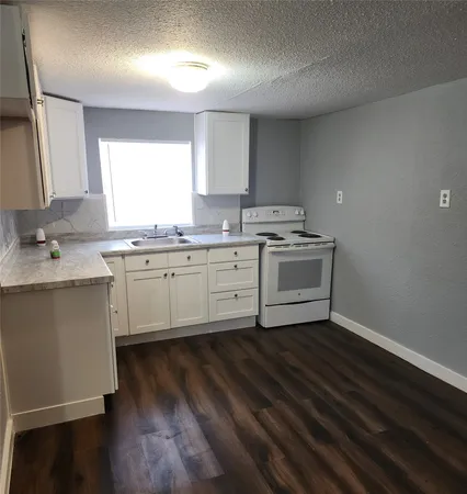 a kitchen with a sink cabinets wooden floor and stainless steel appliances