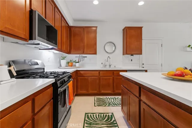 a kitchen with stainless steel appliances granite countertop a stove a refrigerator a sink a dining table and chairs with wooden floor