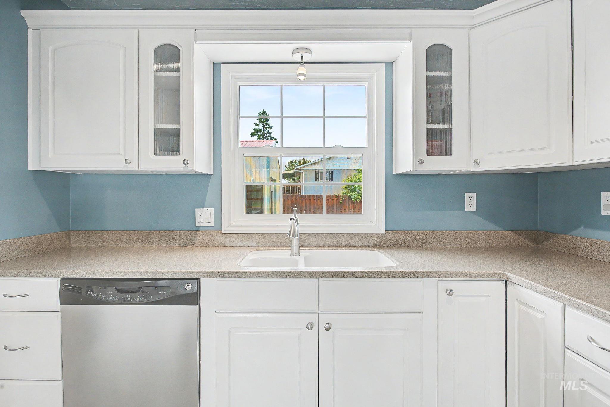 3314 6th Street Lewiston, ID 83501 - Photo 14 of 50 Kitchen featuring white cabinetry, a double basin sink, a stainless steel dishwasher, a window with grid inserts, and light-colored countertops