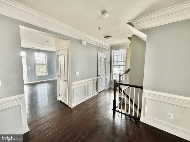 a view of a hallway with wooden floor and stairs