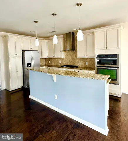 a kitchen with stainless steel appliances granite countertop a refrigerator a stove and a wooden floors