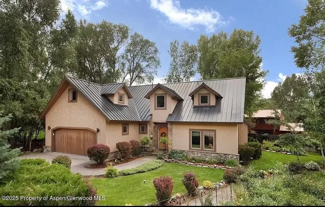 a front view of house with yard and trees in the background