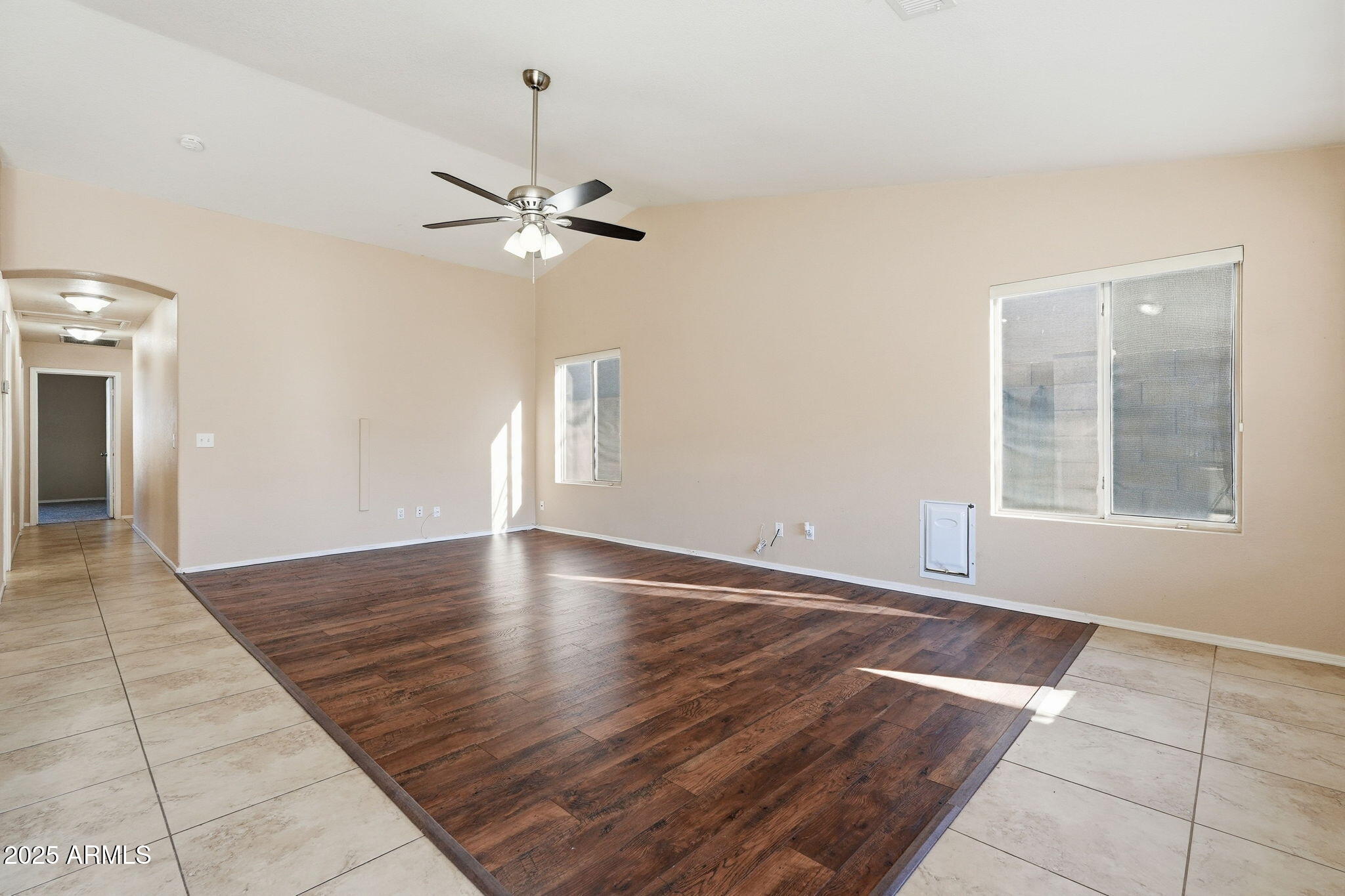 1619 East Carter Road Phoenix, AZ 85042 - Photo 13 of 56 an empty room with wooden floor chandelier fan and windows