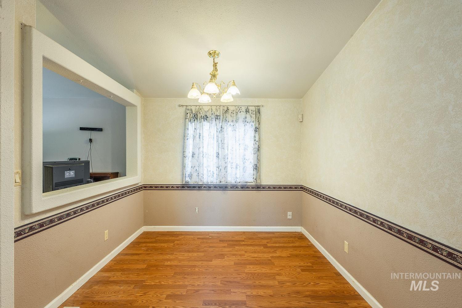4119 Ashton Avenue Caldwell, ID 83607 - Photo 12 of 50 Unfurnished dining area with hanging lights, wood finished floors, and a textured wall