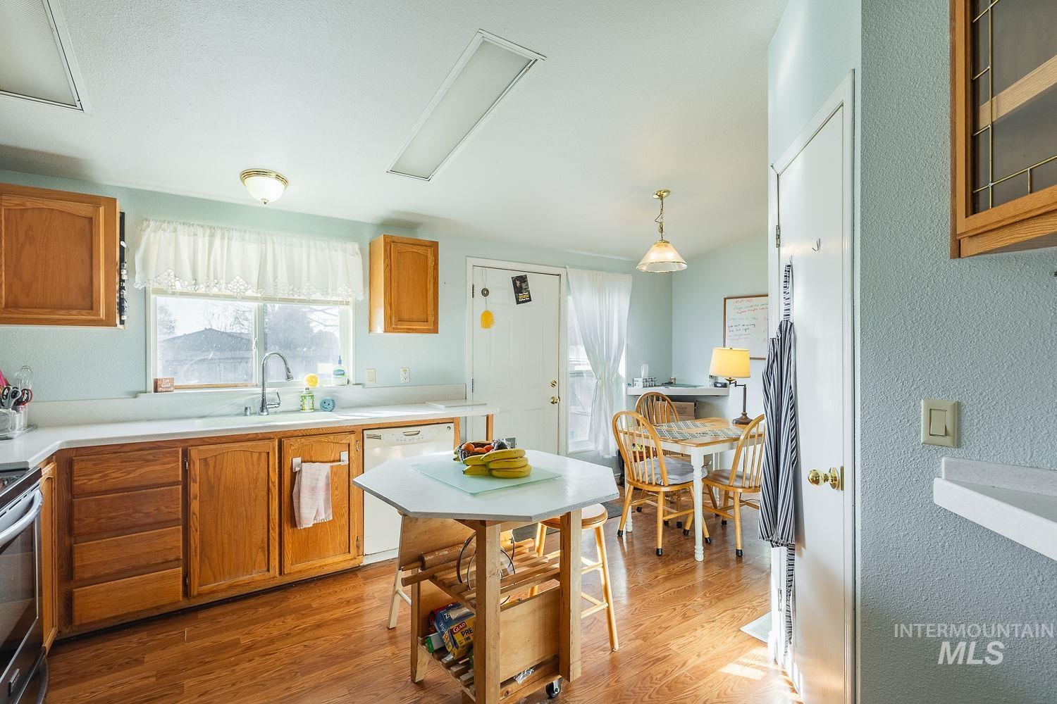 4119 Ashton Avenue Caldwell, ID 83607 - Photo 14 of 50 Kitchen with wood finish cabinetry, light countertops, hanging light fixtures, dishwasher, and a textured wall