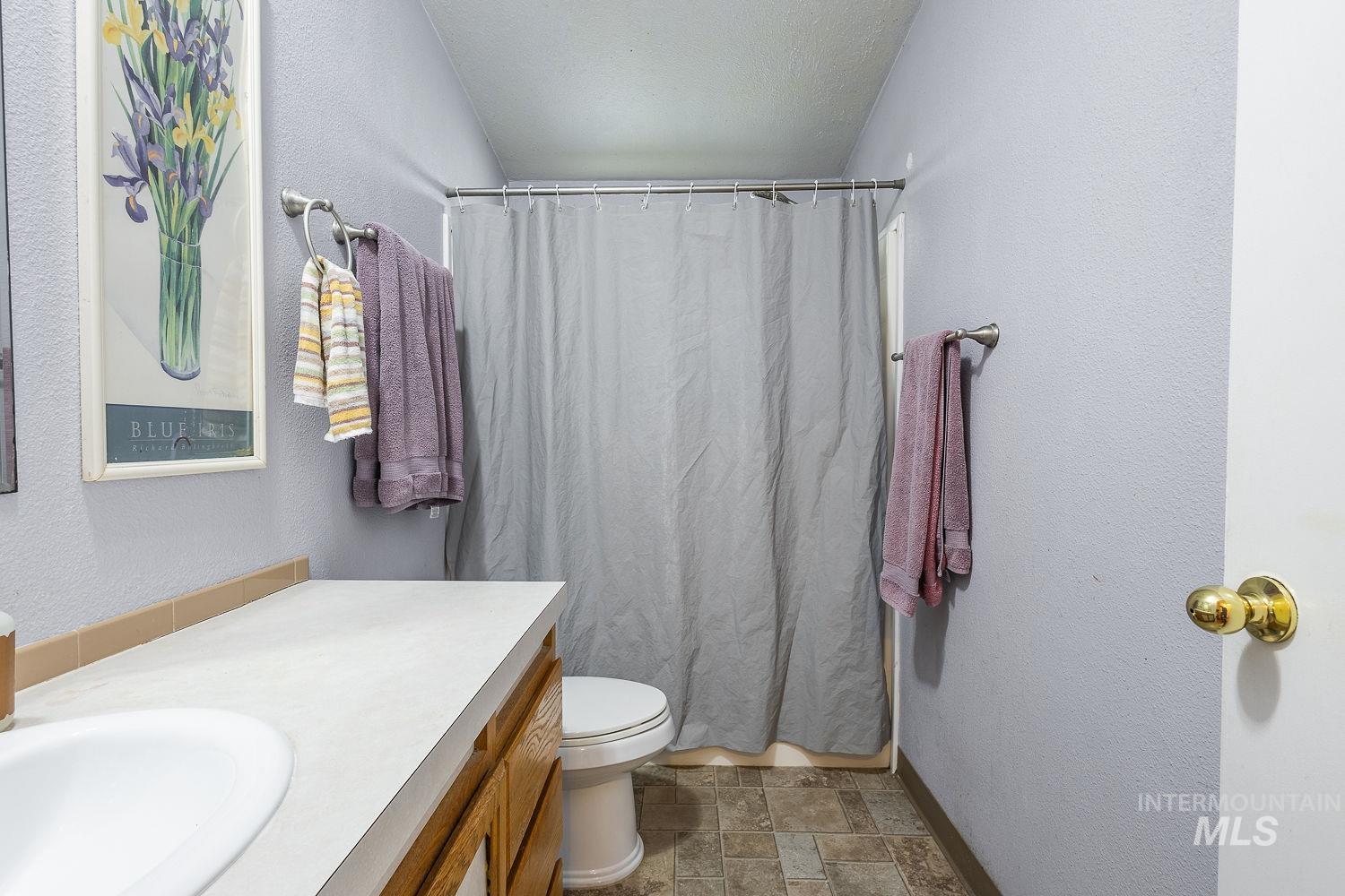 4119 Ashton Avenue Caldwell, ID 83607 - Photo 36 of 50 Bathroom with a textured wall, curtained shower, stone finish floors, and vanity