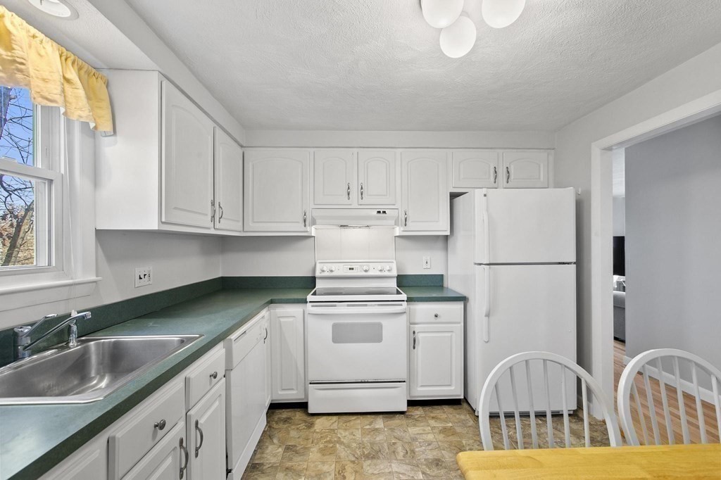 6 Dundee Road, Unit 6 Arlington, MA 02476 - Photo 13 of 29 a kitchen with a sink a refrigerator and cabinets