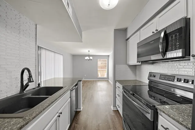 a kitchen with stainless steel appliances granite countertop a sink a stove top oven and refrigerator