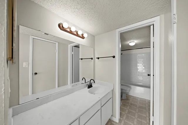 an empty room with a chandelier fan and wooden floor