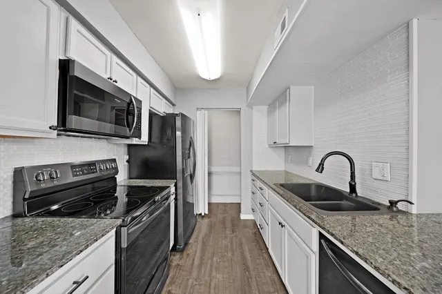 a view of a room with wooden floor a chandelier and windows