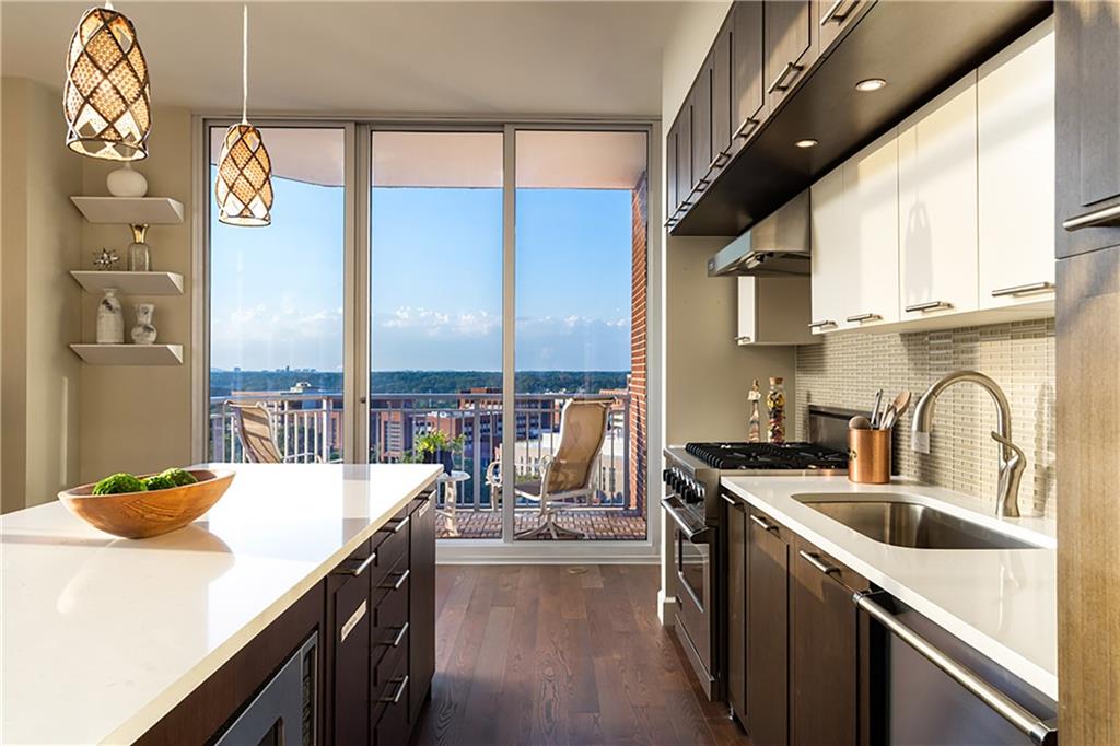 1820 Peachtree Road Northwest, Unit 1408 Atlanta, GA 30309 - Photo 9 of 37 a kitchen with stainless steel appliances a sink a stove top oven a chimney and a center island
