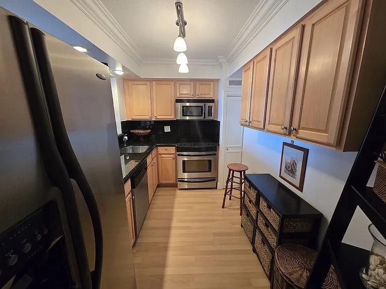 1900 South Ocean Boulevard, Unit 11L Lauderdale-by-the-Sea, FL 33062 - Photo 16 of 16 a kitchen with granite countertop a refrigerator a stove a sink dishwasher and wooden cabinets