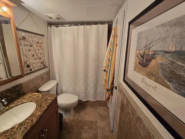 a bathroom with a granite countertop sink toilet and shower