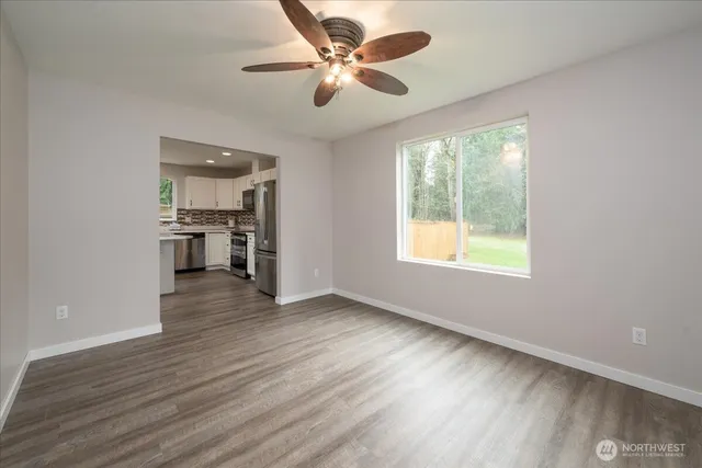 an empty room with wooden floor chandelier fan and windows