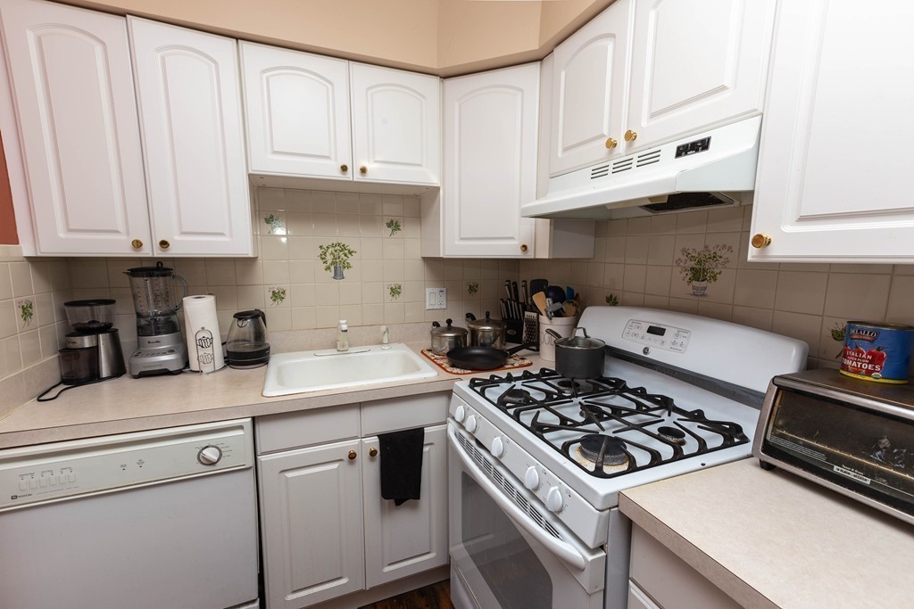 116 Sutherland Road, Unit 2 Boston, MA 02135 - Photo 7 of 10 a kitchen with stainless steel appliances granite countertop white cabinets and a stove a oven with white countertops