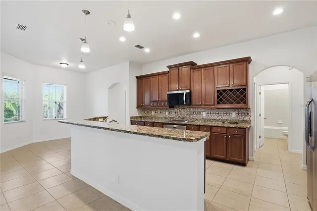 a kitchen with stainless steel appliances granite countertop a stove top oven a sink and a refrigerator