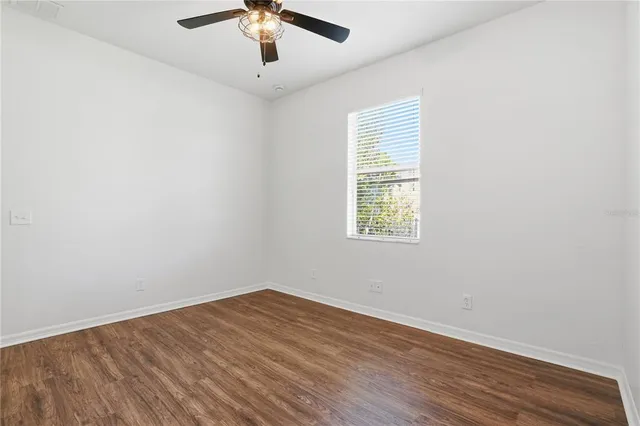 an empty room with a window and a ceiling fan