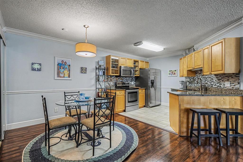 1550 South Belcher Road, Unit 525 Clearwater, FL 33764 - Photo 15 of 28 a kitchen with stainless steel appliances granite countertop a stove a refrigerator a kitchen island with chairs and wooden floor