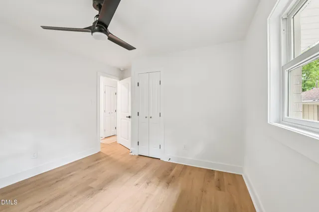 a view of empty room with wooden floor and fan