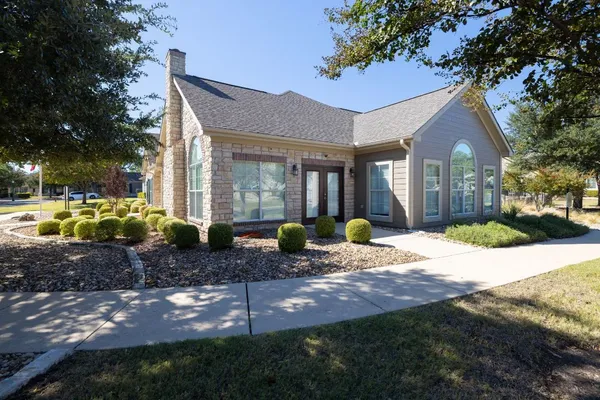 a front view of a house with a yard outdoor seating and covered with trees