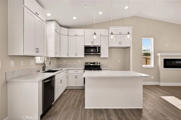 a kitchen with stainless steel appliances granite countertop a stove top oven a sink and white cabinets