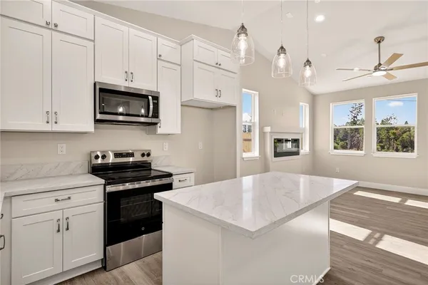 a kitchen with stainless steel appliances a stove a sink a refrigerator white cabinets and wooden floor
