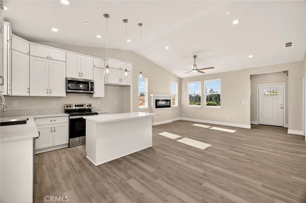 a kitchen with stainless steel appliances granite countertop a stove top oven a sink and white cabinets with wooden floor