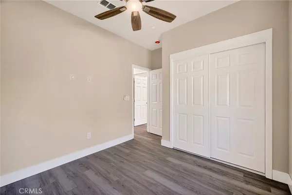 an empty room with a ceiling fan and wooden floor