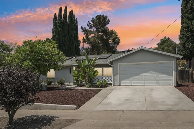 a front view of a house with a yard and trees